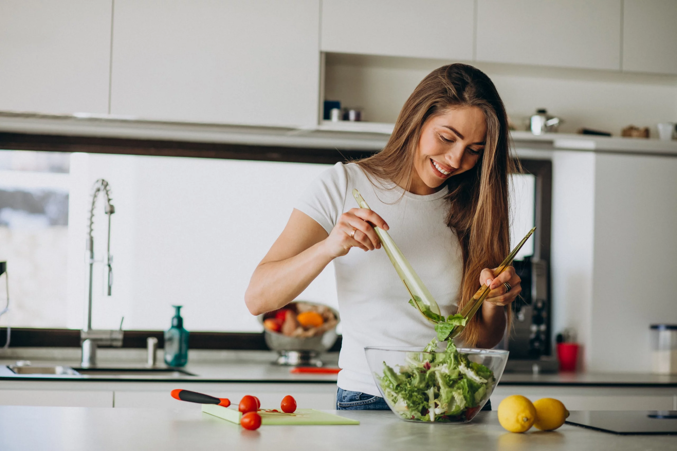 Alimentation saine et équilibrée à Genève Femme souriante préparant une salade fraîche dans sa cuisine, symbole de nutrition équilibrée à Genève